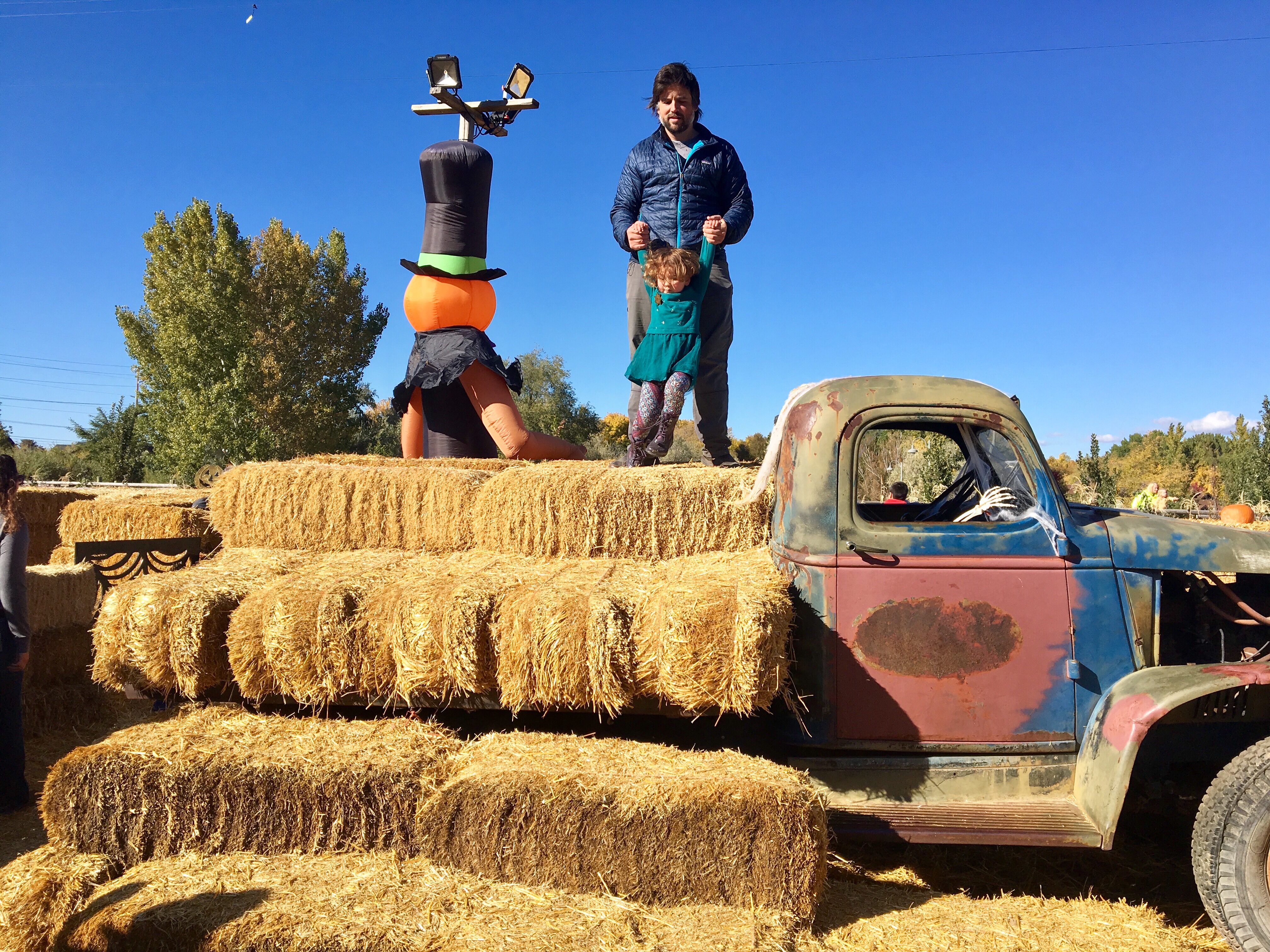 Dada and daughter on hay bales with truck